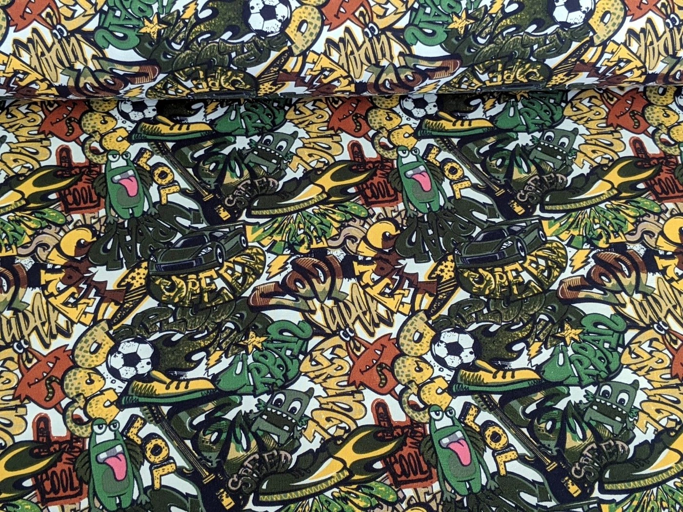 Corileo Stoff »Baumwolljersey Comic Graffiti Kids Fussball Grün Stoff Meterware Jersey«