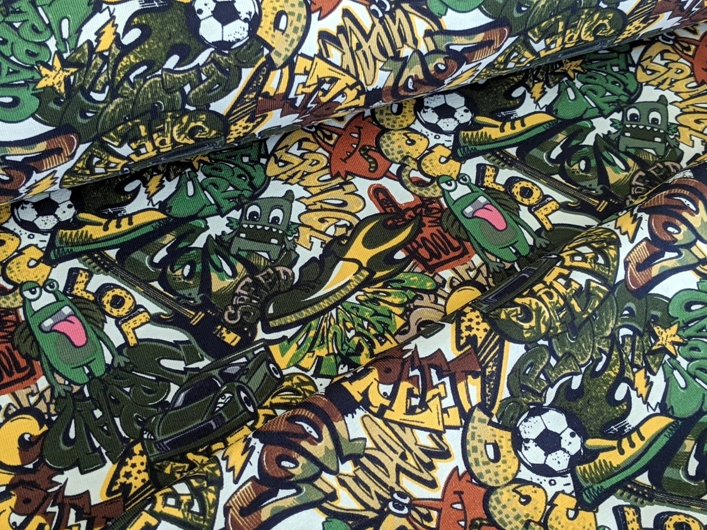 Corileo Stoff »Baumwolljersey Comic Graffiti Kids Fussball Grün Stoff Meterware Jersey«